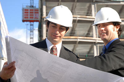 Obraz z dwoma łebkami w kasku pochylającymi się nad rysunkiem technicznym przy budowie